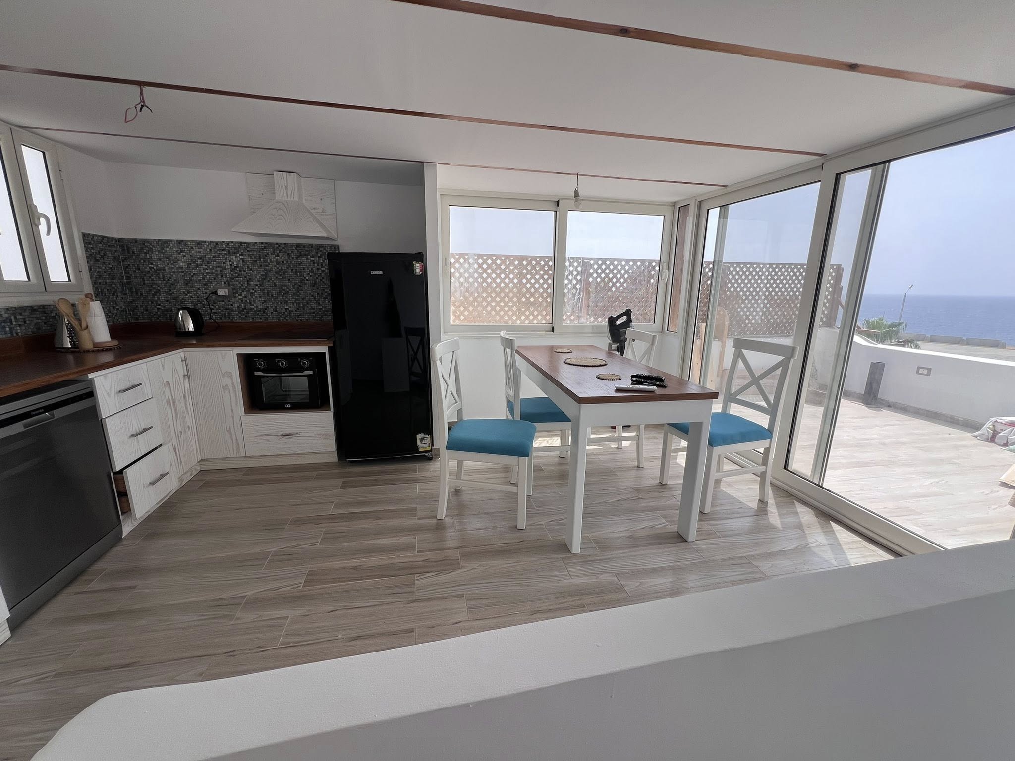 Above It All Rooftop kitchen with sea view, glass walls, and dining table